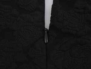 Detail der floralen Jacquard-Struktur und verdeckter Reißverschluss am schwarzen Kleid