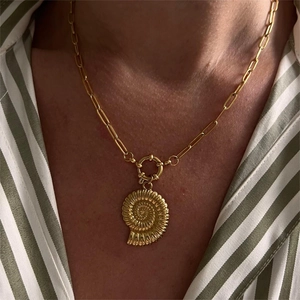 Golden nautilus shell pendant on rectangular link chain necklace worn on striped shirt