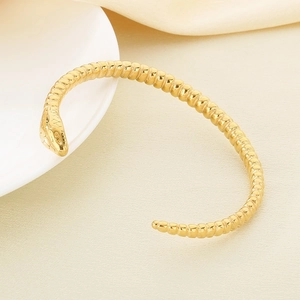 Detailed view of golden snake-scale texture and open cuff design on metal bracelet