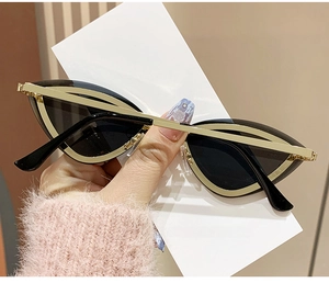 Détail de lunettes de soleil œil-de-chat sans monture avec rivets dorés et verres foncés