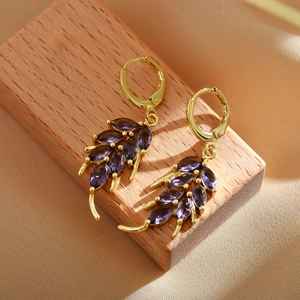 Macro view of gold leaf drop earrings featuring marquise-cut deep purple gemstones