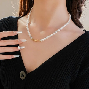 Detail of vintage pearl necklace with a gold magnetic clasp worn on a black V-neck top