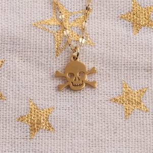 Detail of a golden skull pendant necklace on beige fabric with decorative gold stars