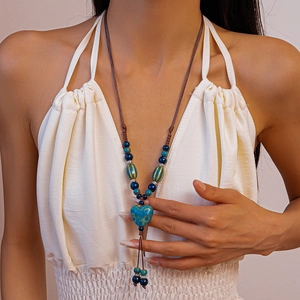 Détail d'un collier bohème avec pendentif cœur en céramique bleu sarcelle et perles