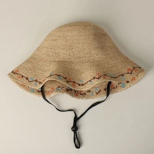 Close-up of beige raffia sun hat featuring exquisite blue and orange floral embroidery