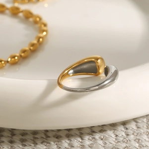 Close-up of two-tone stainless steel teardrop ring and gold olive bead bracelet set