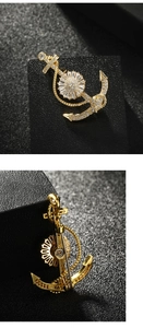 Detailed front and back view of a golden anchor brooch with sparkling zircon inlays