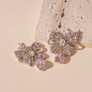 Detail of silver bow earrings with pink heart crystals and teardrop tassel pendants