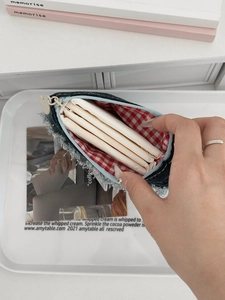 Denim bow storage bag with red gingham lining showing capacity for sanitary pads