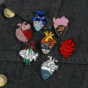 Set of seven creative anatomical heart enamel pins with diverse artistic patterns on denim