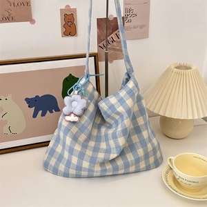 Detailed close-up of blue and white checkered canvas tote bag with a floral pendant