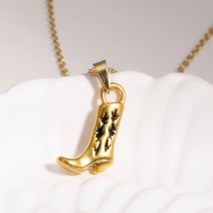Vue macro d'un pendentif botte de cowboy dorée avec émail noir sur support blanc