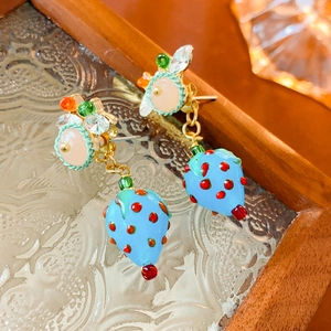 Detailed macro of resin strawberry earrings with pink beads and colorful crystals