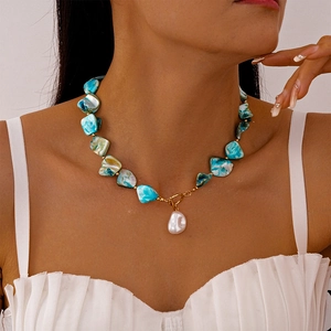 Dettaglio della collana con conchiglie blu, ciondolo a perla barocca e chiusura a T in oro