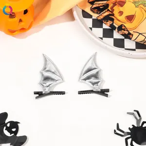 Pair of silver bat wing hair clips with black metal crocodile grip on festive background