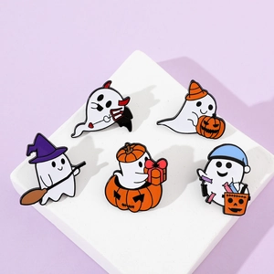 Detail of five Halloween ghost and pumpkin enamel pins set on a stone base