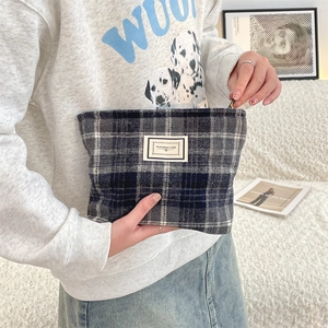 Close-up of vintage plaid tweed cosmetic bag featuring a woven texture and woven label