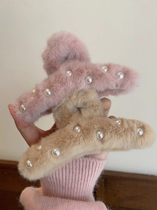 Detail of plush faux fur hair claws in pink and beige featuring faux pearl accents