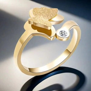 Détail d'une bague dorée réglable avec aile de papillon texturée et une pierre brillante