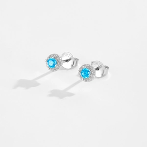 Close-up of S925 sterling silver earrings with sky blue round stones and halo diamonds
