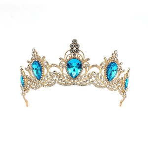 Close-up of golden baroque crown with blue teardrop gems and white rhinestones