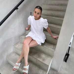 Haut babydoll blanc à manches bouffantes et nœud dans le dos porté par un mannequin