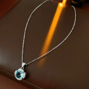 Macro view of blue zircon flower pendant with silver chain on leather surface