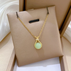 Close-up of gold lucky bag necklace with green stone and pavé zircons in a gift box
