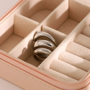 Close-up of three silver-tone 18k gold-plated stainless steel spring-style rings on pink leather