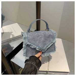 Detail of light blue denim handbag with frayed fringe edges and silver chain strap