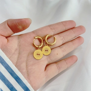Macro shot of 18K gold plated stainless steel starburst eye earrings held by hand