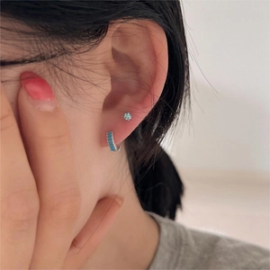 Macro shot of 925 sterling silver hoop earrings with sky blue stones worn on ear