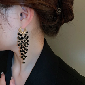 Macro detail of elegant black geometric crystals on golden layered tassel drop earrings