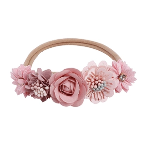 Close-up of pink fabric flowers and faux pearls on a soft elastic baby headband