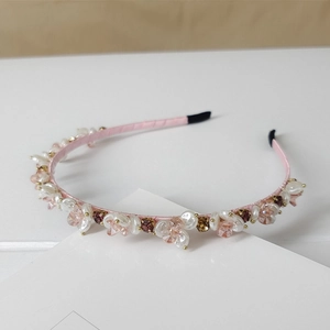 Detail of pink satin headband featuring crystal beads and faux pearls with soft lighting
