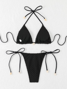 Flat lay of black bikini with natural seashell charms and textured crinkle fabric