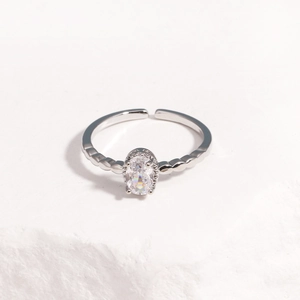 Detail of silver adjustable ring with oval zircon and beaded texture on white stone