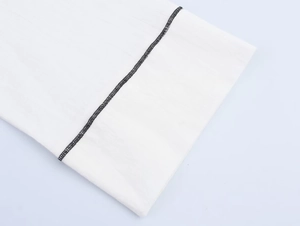 Gros plan détaillé du tissu blanc avec passepoil contrasté noir et coutures de précision