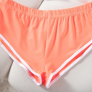 Detail der orangefarbenen Yoga-Shorts mit weißen Paspeln und elastischem Strickgewebe