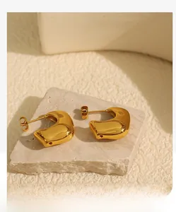 Close-up of chunky gold C-shaped earrings with organic curves on textured stone