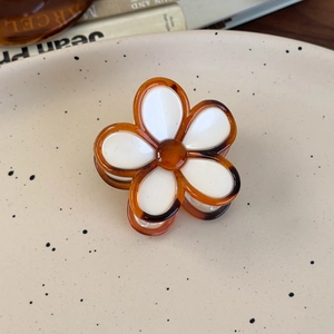 Detailed close-up of amber flower hair claw clip with white petals and resin finish