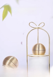 Macro detail of luxury 30g gold cream jar with elegant metal wire bow stand