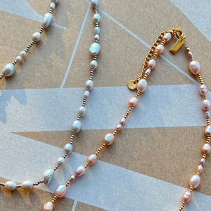 Detail view of gold and silver chains with baroque pearls and lobster clasp closure