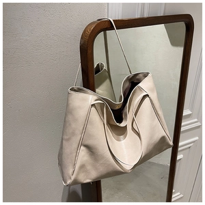 Minimalist beige soft leather tote bag hanging on a mirror in a modern interior setting