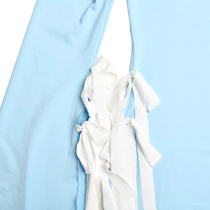 Detailed close-up of light blue fabric with stylish white lace-up tie design on dress