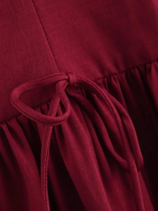 Detailed macro view of the dark red waist tie knot and woven fabric texture on the dress