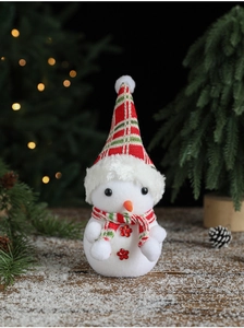 Close-up of white flocked snowman doll with plaid hat and scarf in festive holiday setting