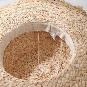 Handwoven straw beach hat with a wide brim, showing detailed 100% paper material texture