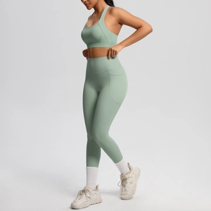 Detail of high-waisted yoga leggings with functional side pockets in light green fabric