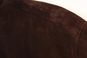 Detail einer dunkelbraunen Wildlederjacke mit präzisen Nähten im Schulterbereich der Jacke